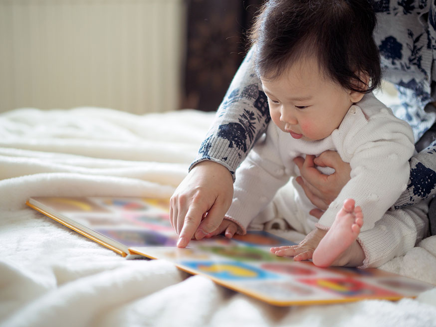 Bebé leyendo un libro con un adulto